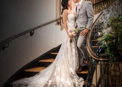 A bride and groom standing on the stairs of an ornate building.